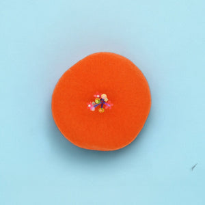 Bright orange beret with floral details